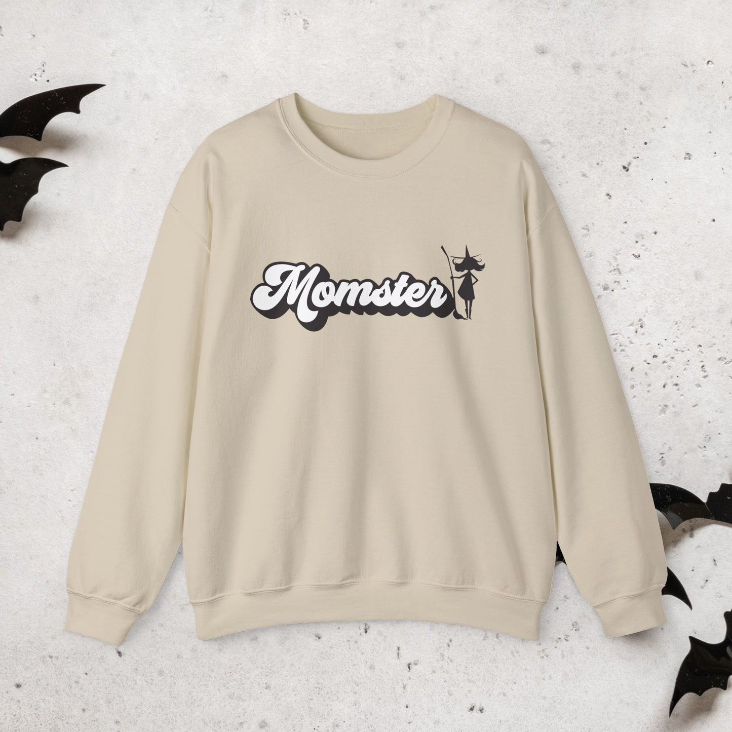 Beige sweatshirt with a Halloween witch 'Momster' design on a textured surface