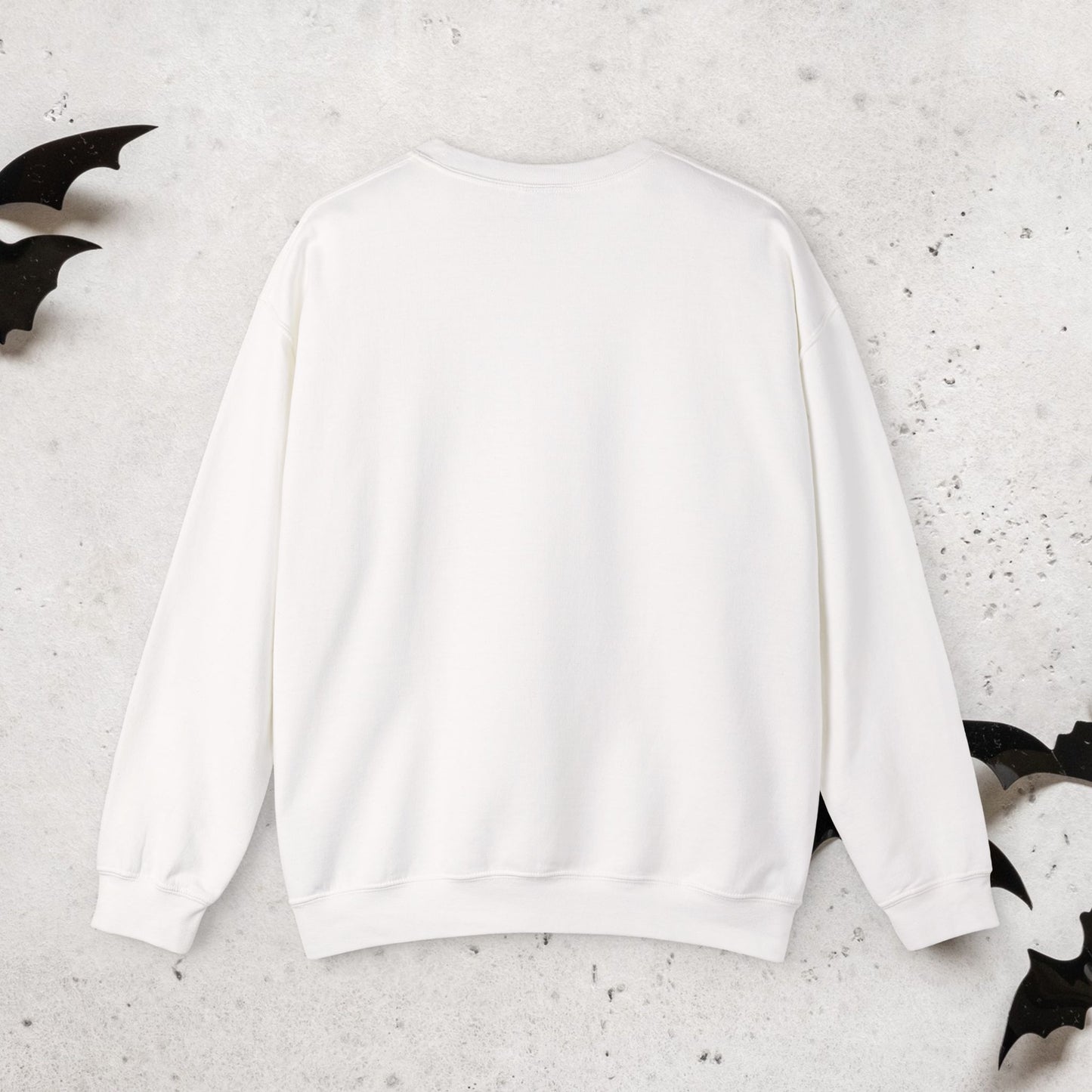 Rear view of white sweatshirt with a Halloween witch 'Momster' design on a textured surface