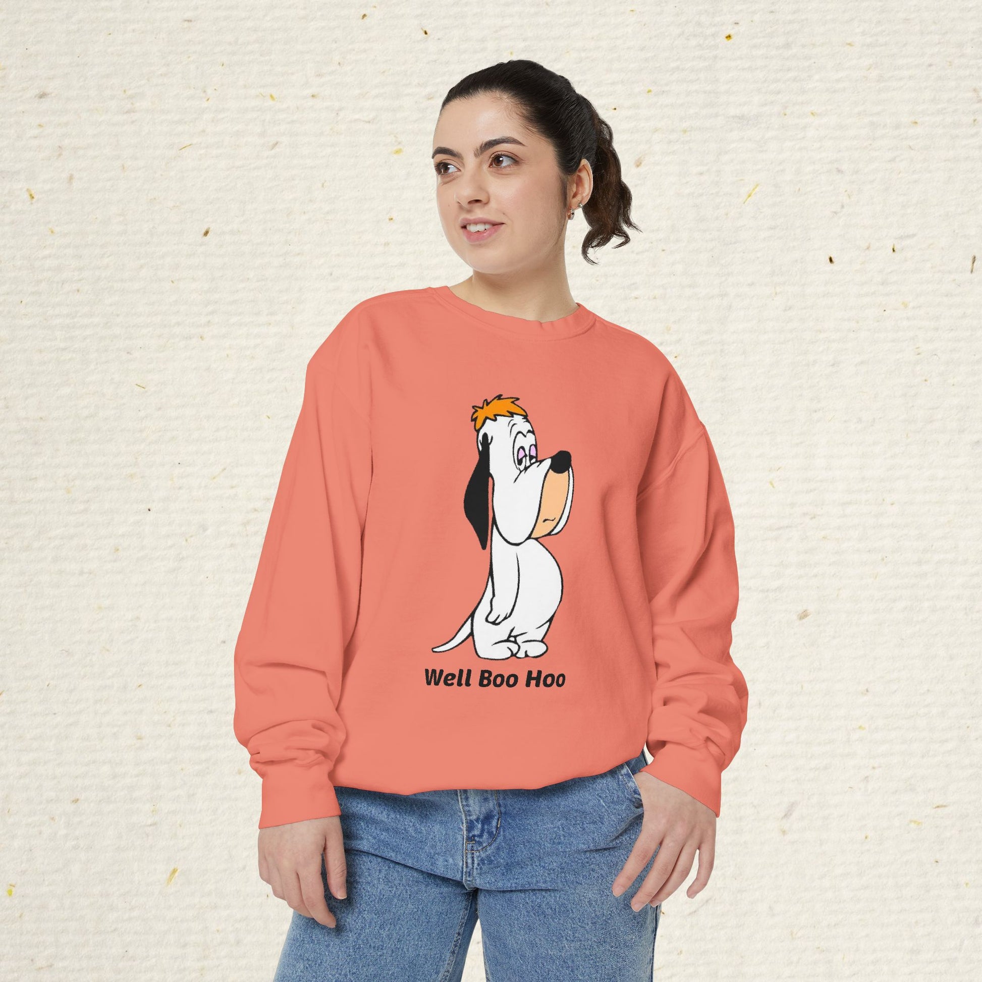 Person wearing a coral sweatshirt with a cartoon droooy dog design and text on a beige background