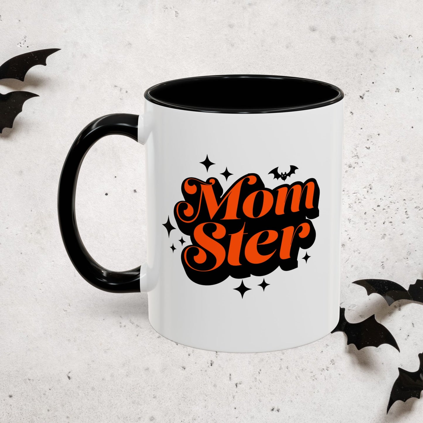 White Halloween mug with black handle featuring 'MomSter' text in orange and black bats on a light gray background.