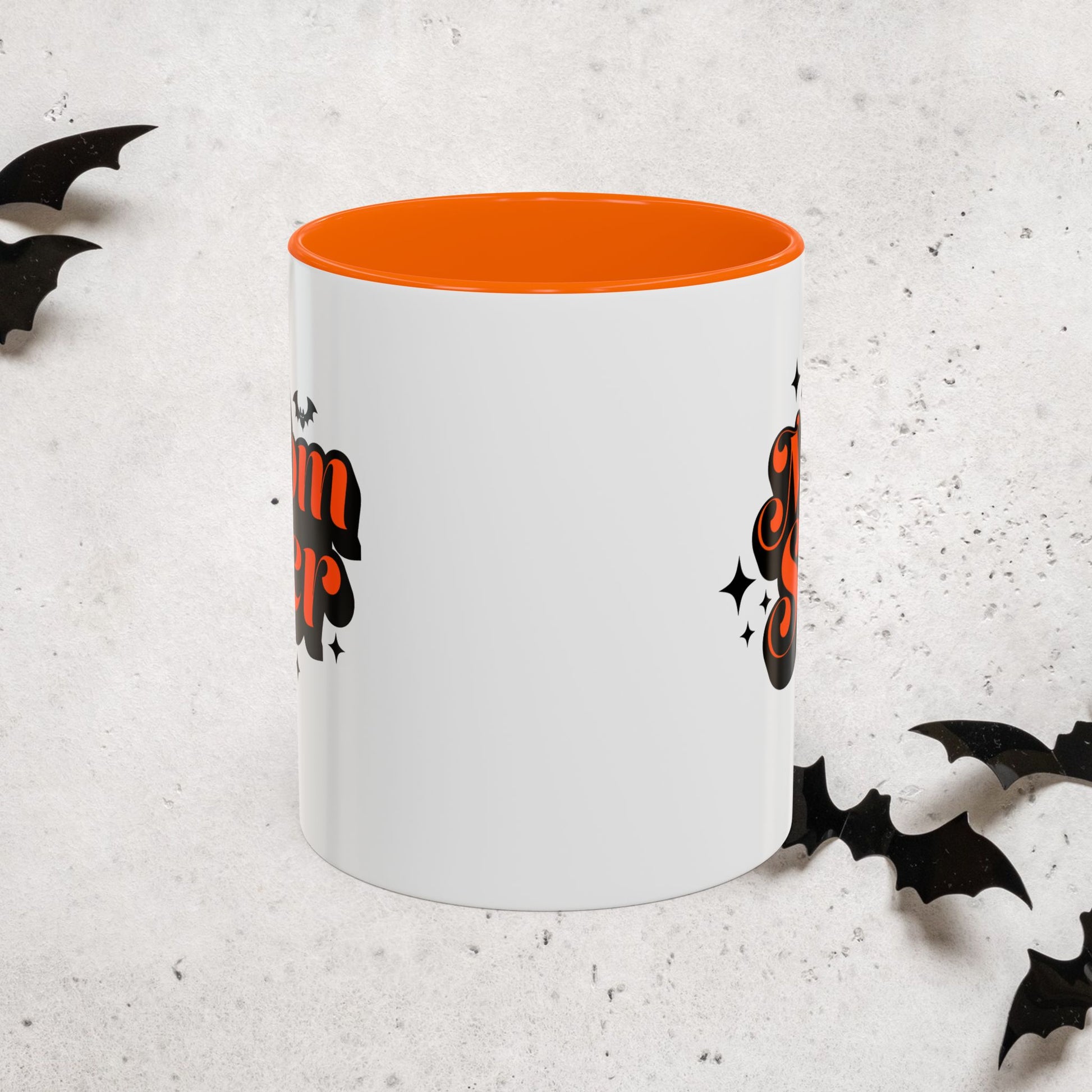 White Momsrer mug with orange interior and Halloween-themed design on a light gray background
