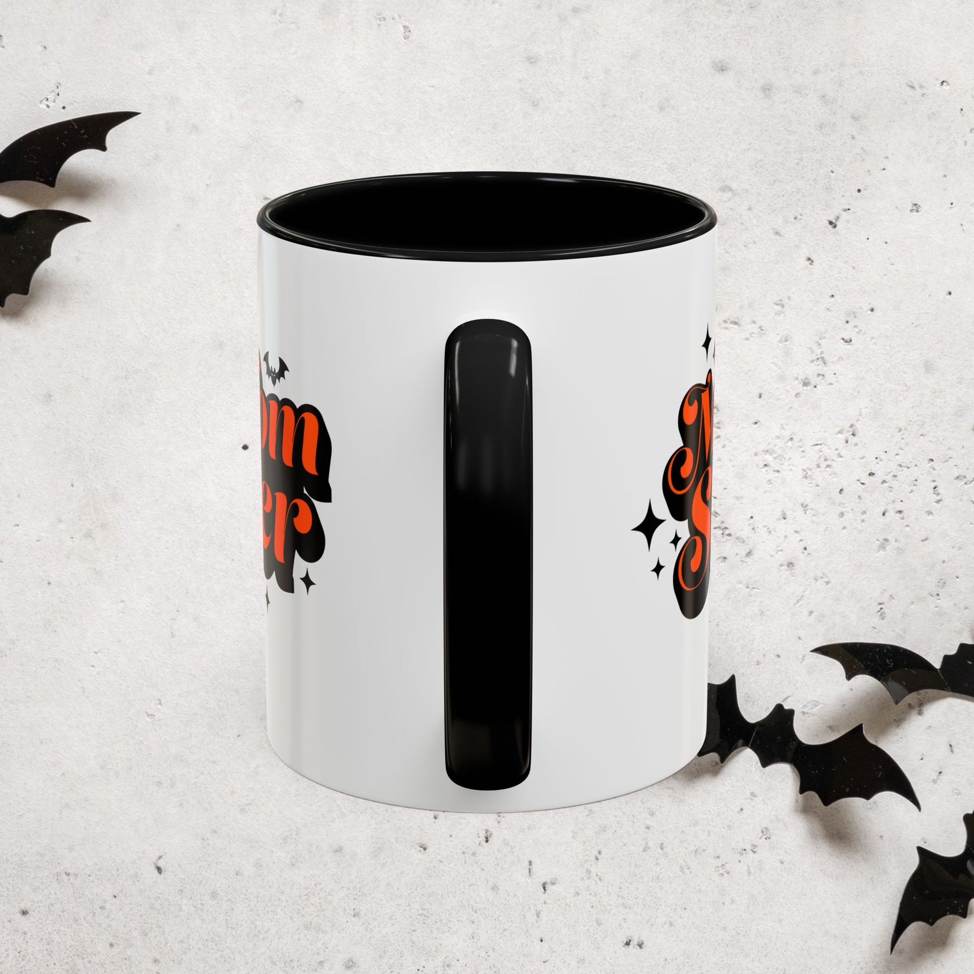 White Momster mug with black interior and handle, featuring Halloween-themed designs on a light gray background.