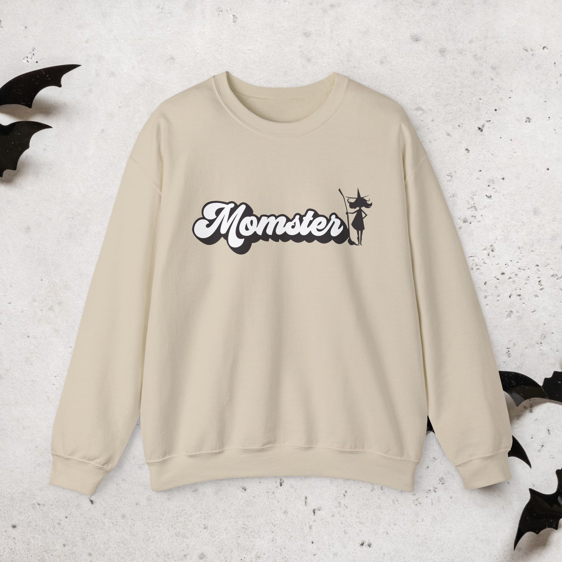 Beige sweatshirt with a Halloween witch 'Momster' design on a textured surface