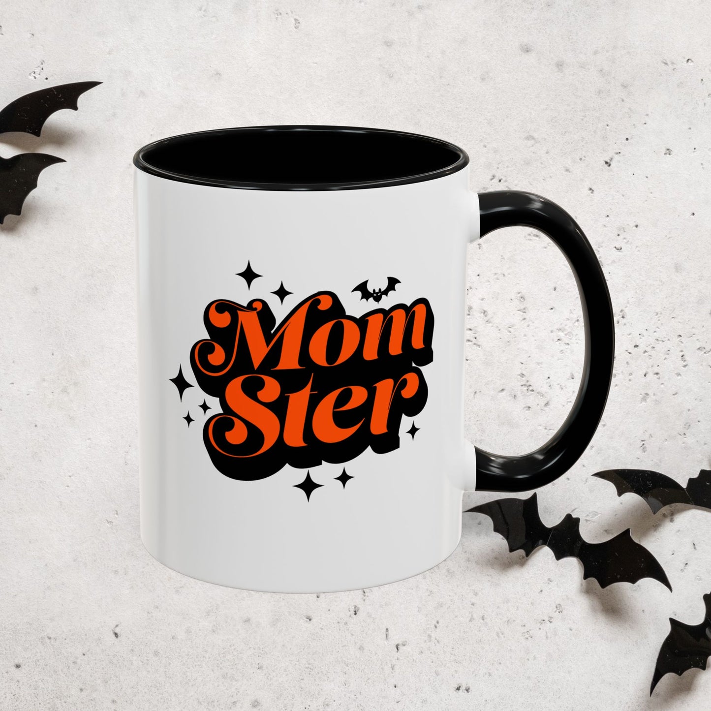 White mug with black interior and handle, featuring 'MomSter' text in orange and black, surrounded by decorative bats on a light gray background.