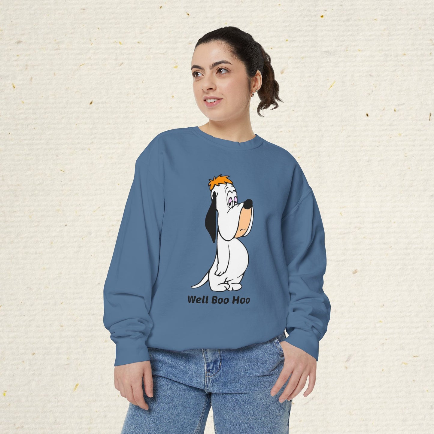 Person wearing a blue sweatshirt with a cartoon droopy dog design on a textured beige background