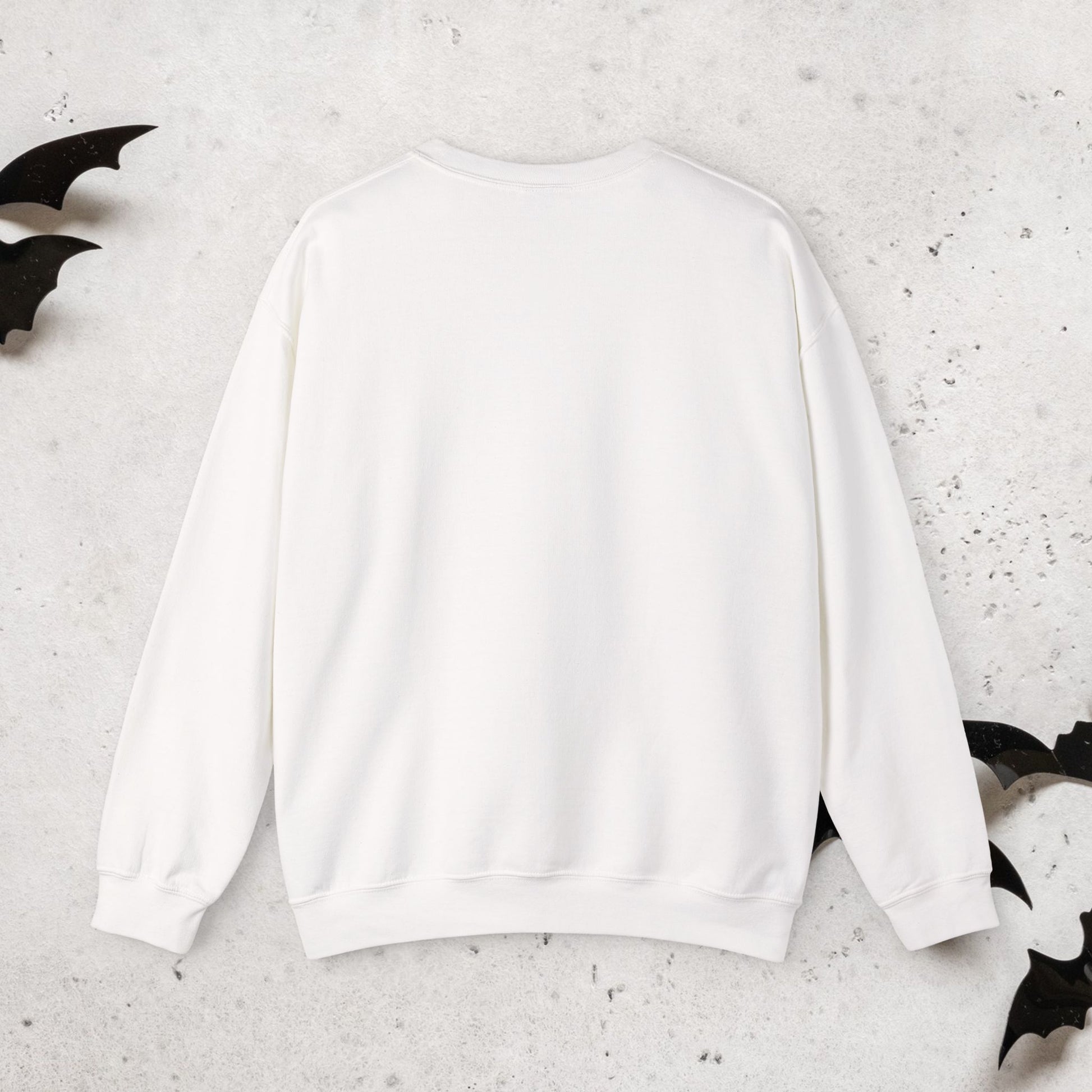 Rear view of white sweatshirt with a Halloween witch 'Momster' design on a textured surface