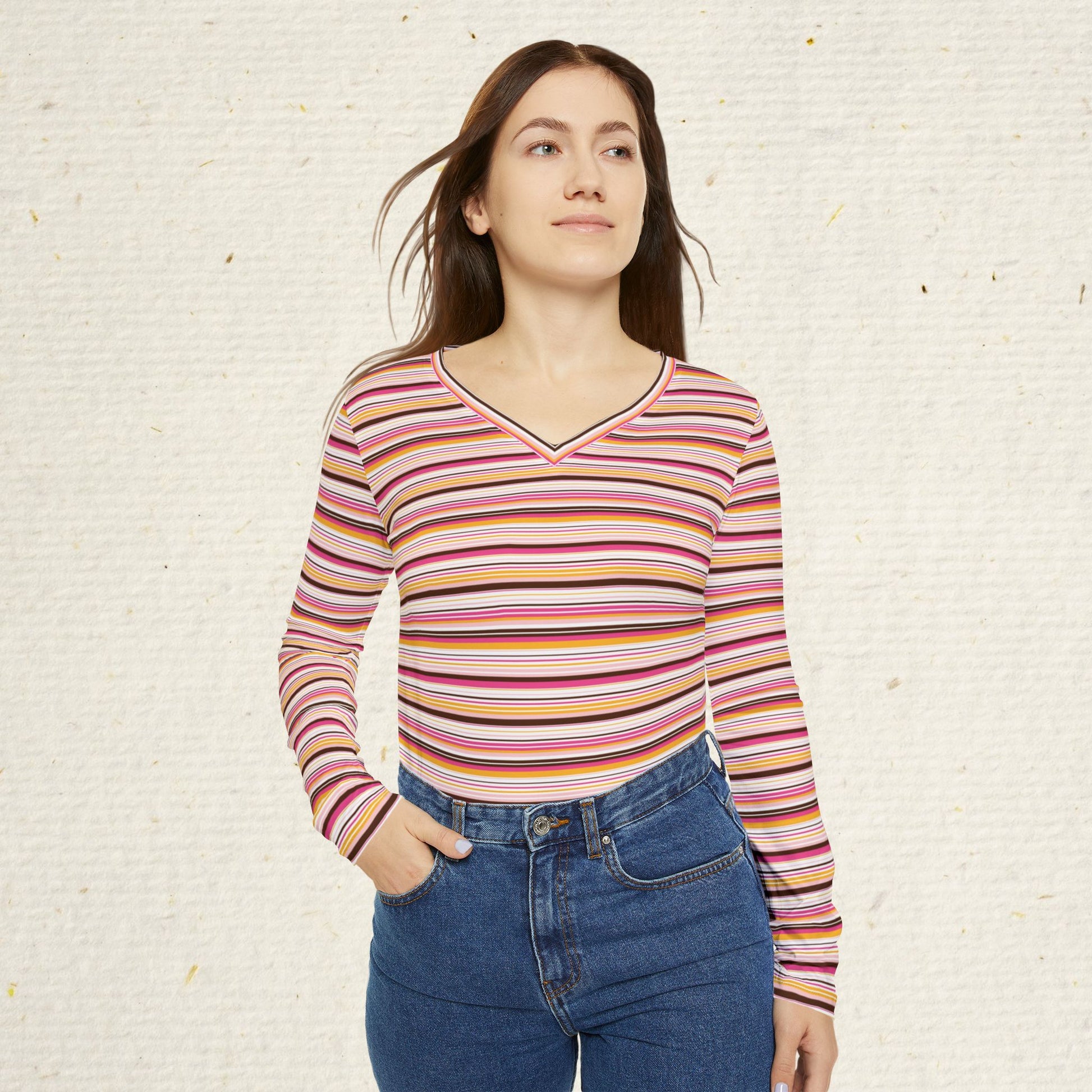 Woman wearing retro striped long sleeve V-neck top with vintage-inspired pink coral and gold stripes paired with jeans.