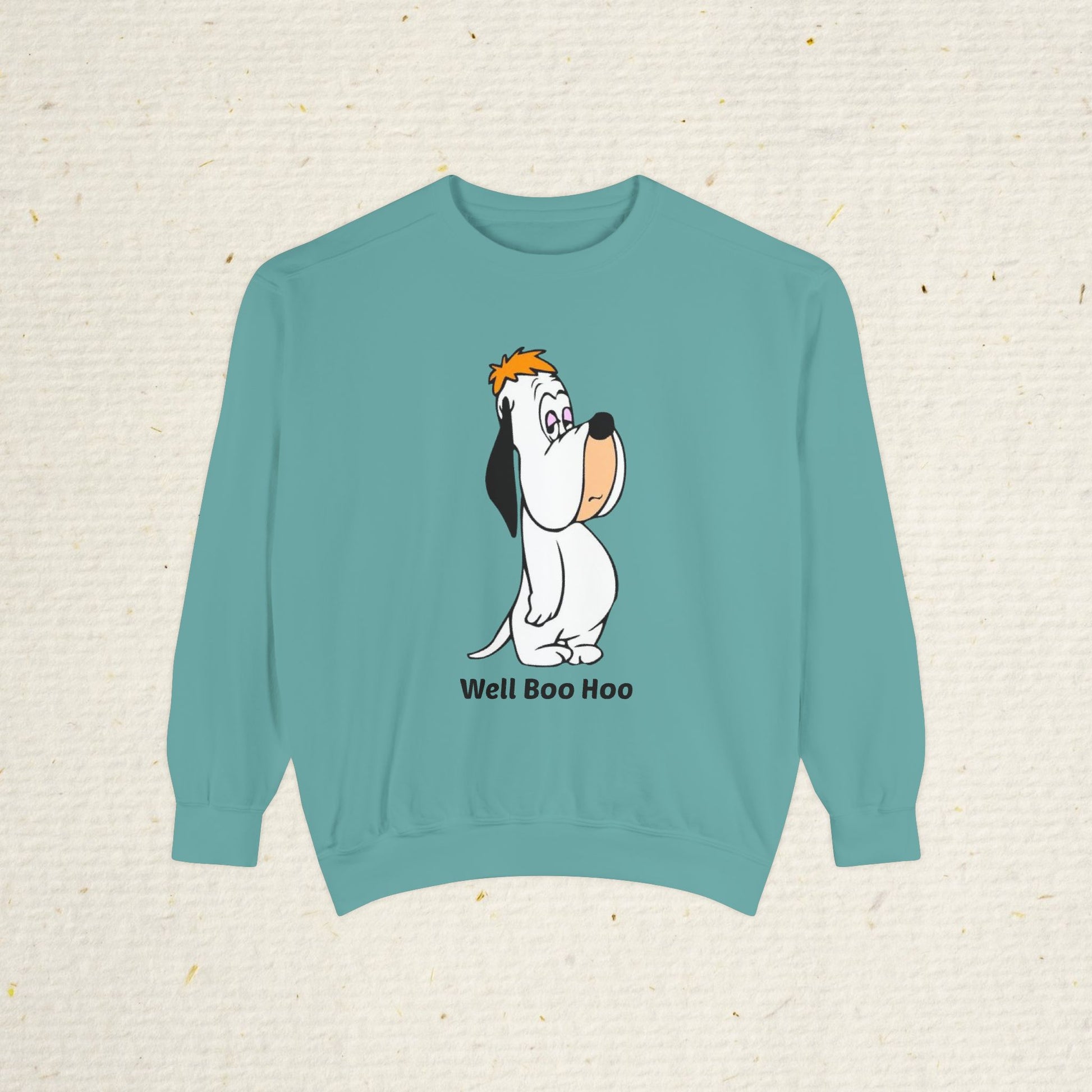 Teal sweatshirt with cartoon droopy dog design and 'Well Boo Hoo' text on a textured beige background