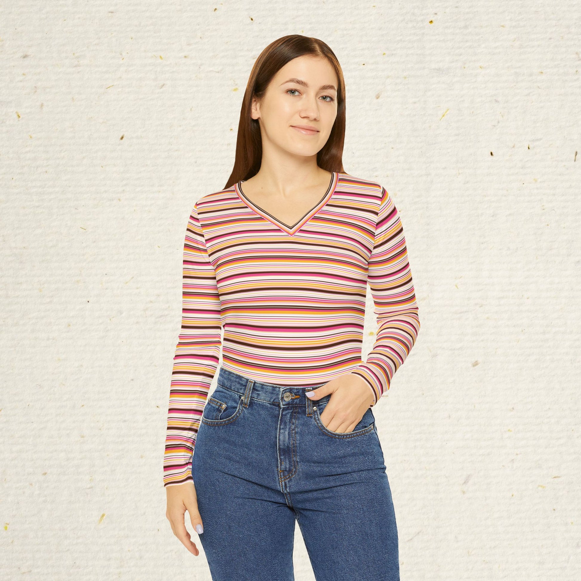 Woman wearing retro striped long sleeve V-neck top with vintage-inspired pink coral and gold stripes paired with jeans.