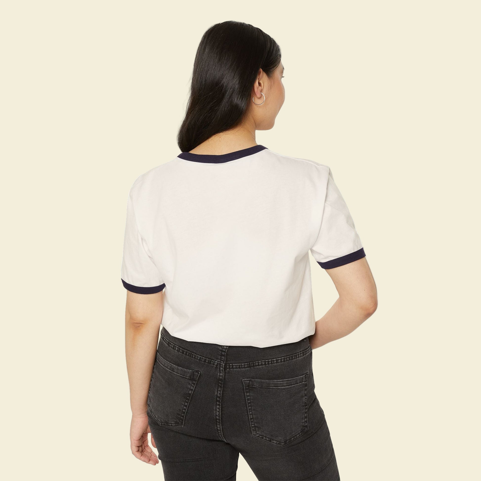 Woman wearing a going back to school t-shirt with navy trim and black pants on a white background
