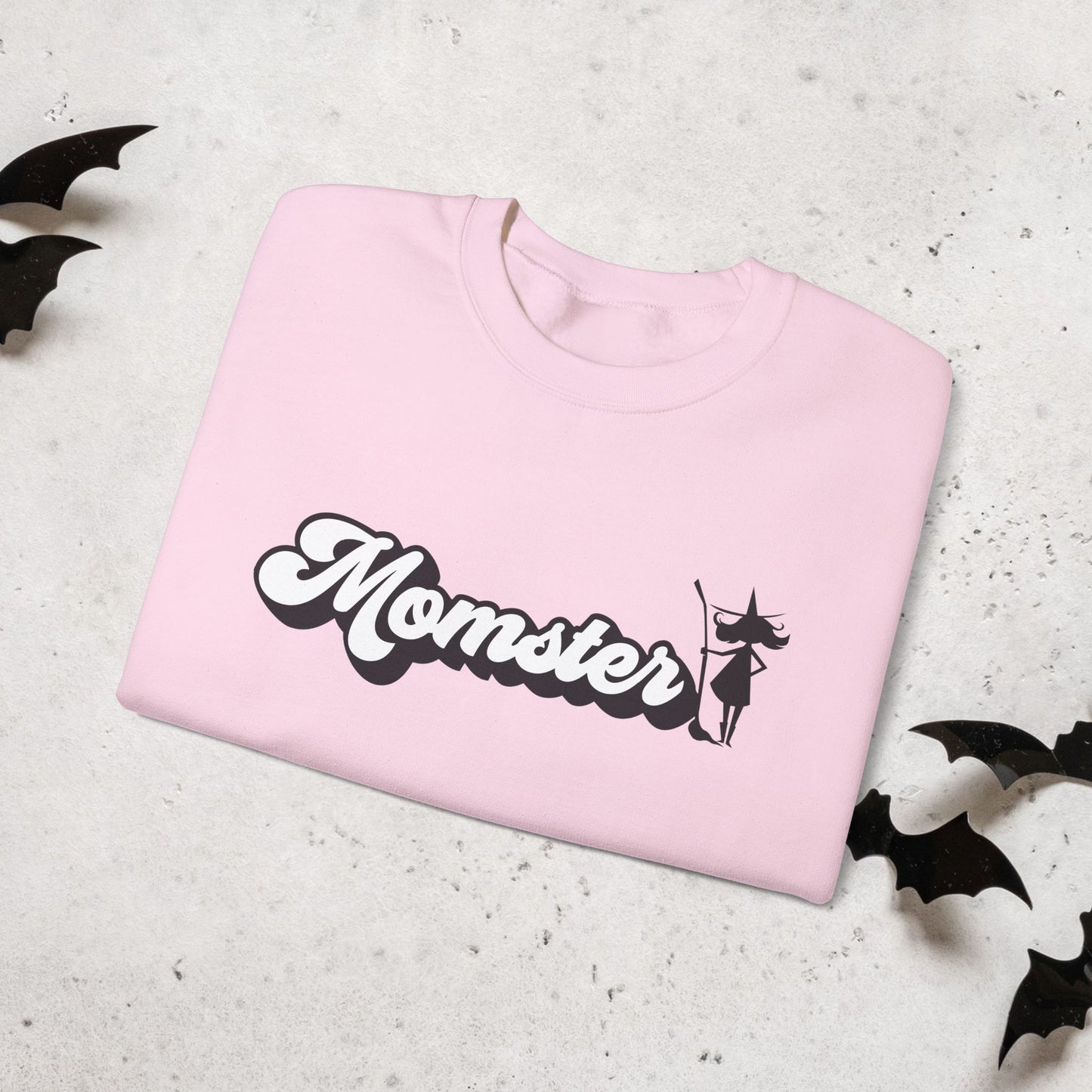 Pink sweatshirt with 'Momster' text and witch graphic on a light gray background