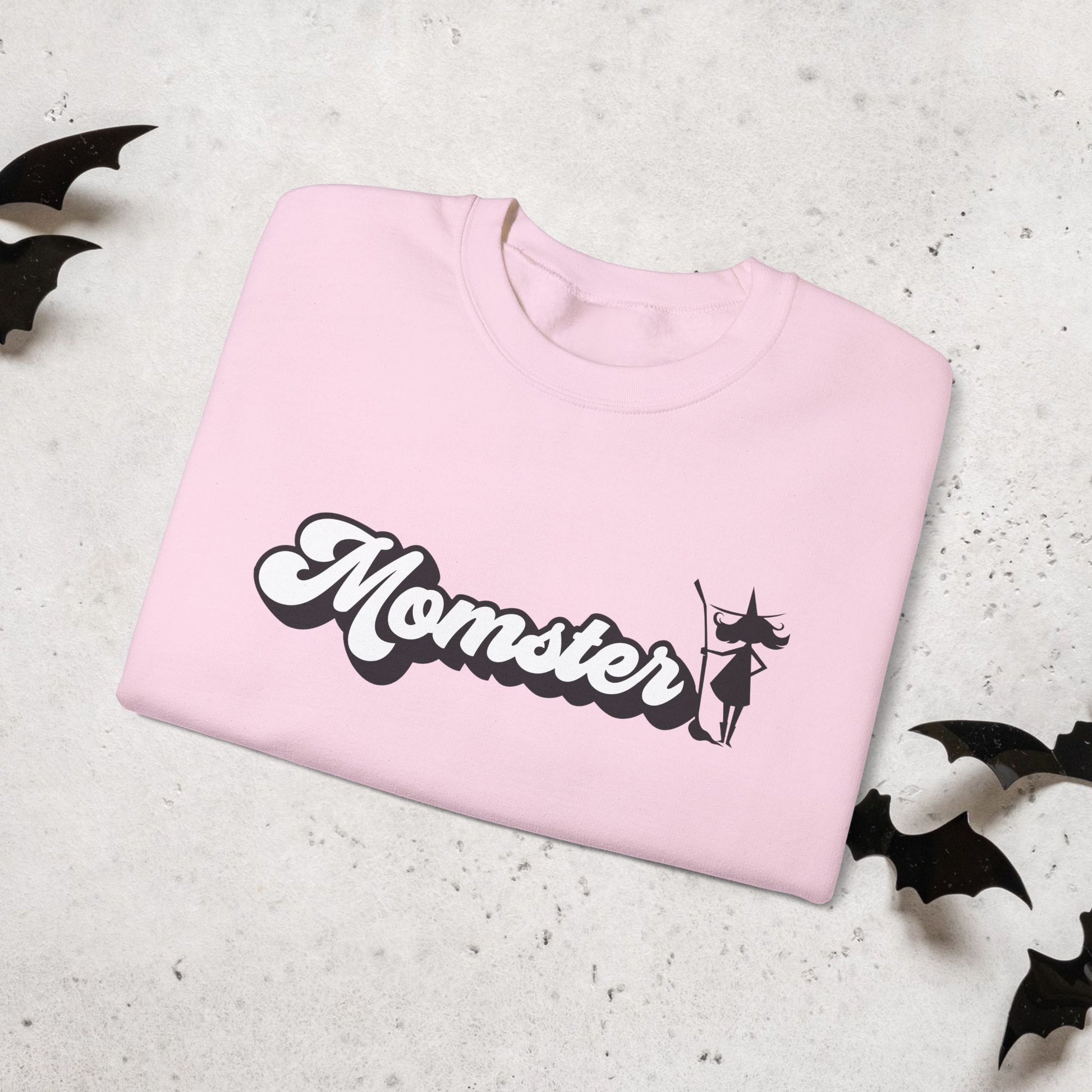 Pink sweatshirt with 'Momster' text and witch graphic on a light gray background