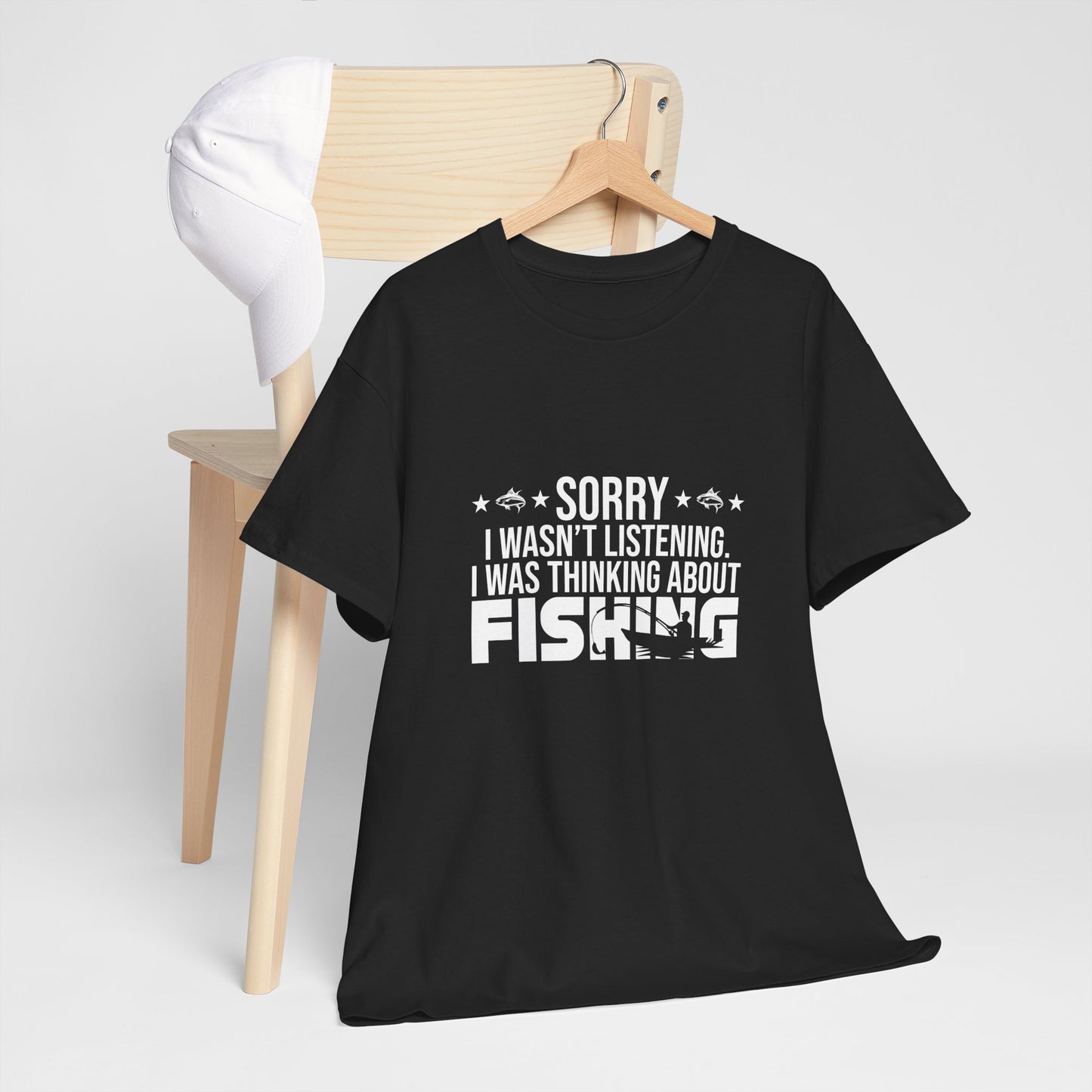 Black t-shirt with 'Sorry I wasn't listening, I was thinking about fishing' text on a hanger against a white background