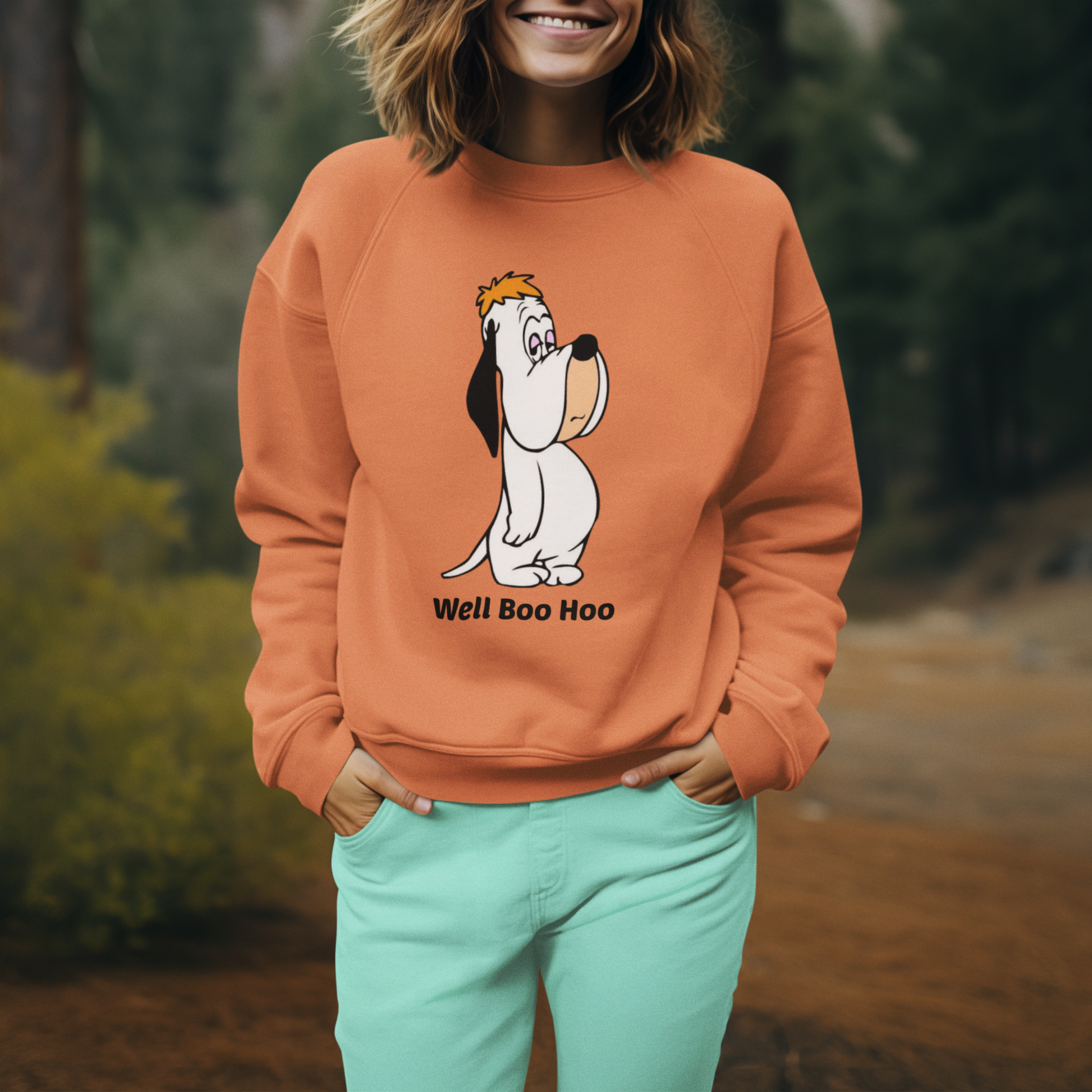 Person wearing an orange sweatshirt with a cartoon Droopy dog design in a forest setting