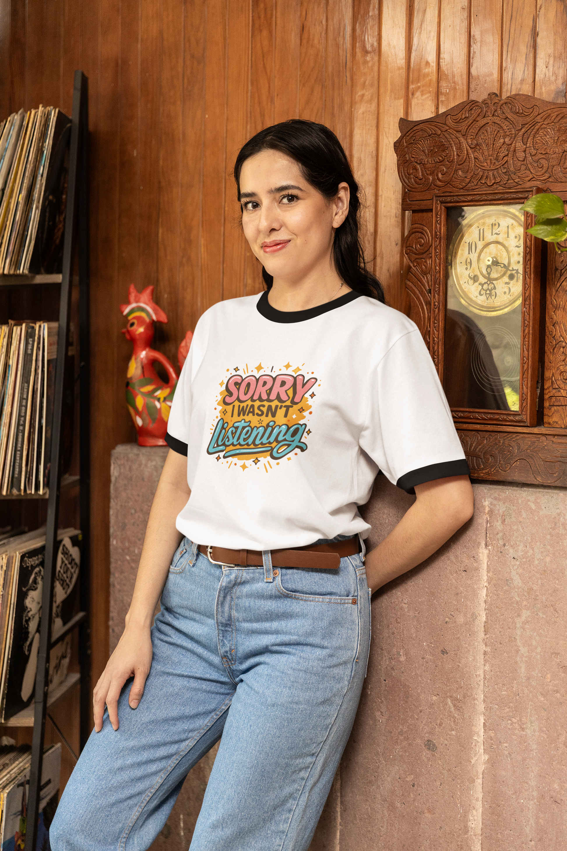 Woman wearing a back to school t-shirt with colorful text design, standing in a room with wooden walls and decorative items.
