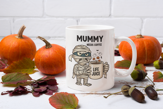 Halloween Mug with mummy design and text 'Mummy needs coffee' on a table with pumpkins and leaves.
